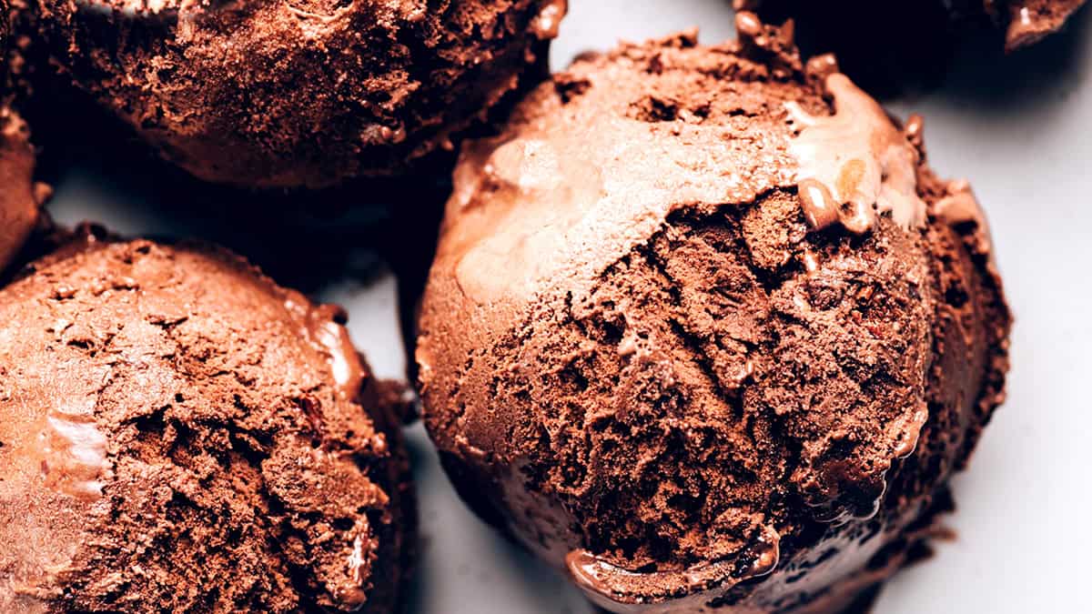 Close-up of several scoops of rich, creamy chocolate ice cream with a slightly melted texture, showing smooth, dense, and textured surfaces—perfect inspiration for your next ice cream recipes.