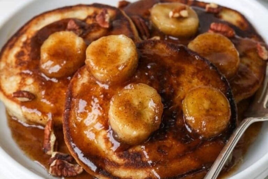A close up image of Bananas Foster on top of a stack of Pancakes.