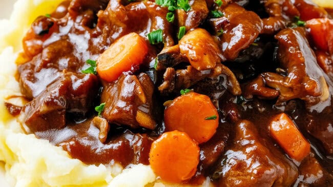 Fluffy mashed potatoes topped with thick brown gravy and braised beef short ribs with carrots and parsley.
