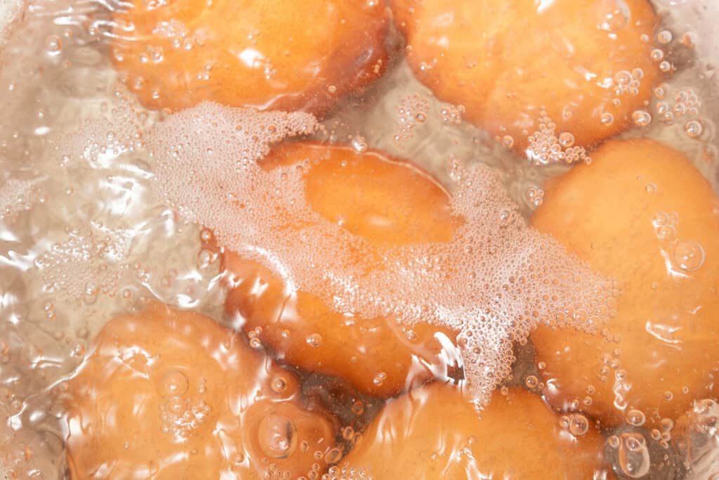 Golden brown fritters frying in hot oil, reminiscent of a classic Southern recipe, surrounded by bubbles and froth.