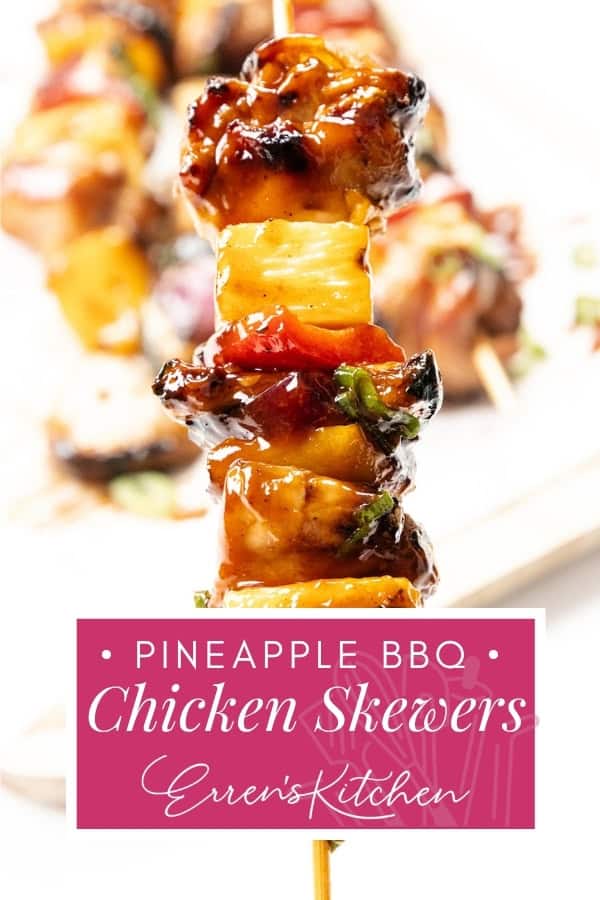 A close-up of juicy BBQ Chicken skewers with pineapple, glazed in sauce and garnished with herbs. More skewers are blurred in the background, and a pink label reads: "Pineapple BBQ Chicken Skewers, Erren's Kitchen.