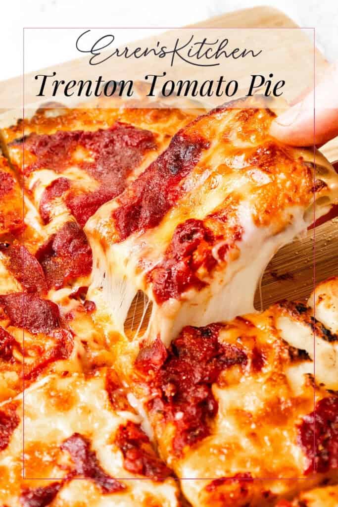 Close-up of a cheesy Trenton Tomato Pie pizza with a hand lifting a slice, showcasing gooey melted cheese and rich tomato sauce on a wooden board. Text overlay reads "Erren’s Kitchen Trenton Tomato Pie.