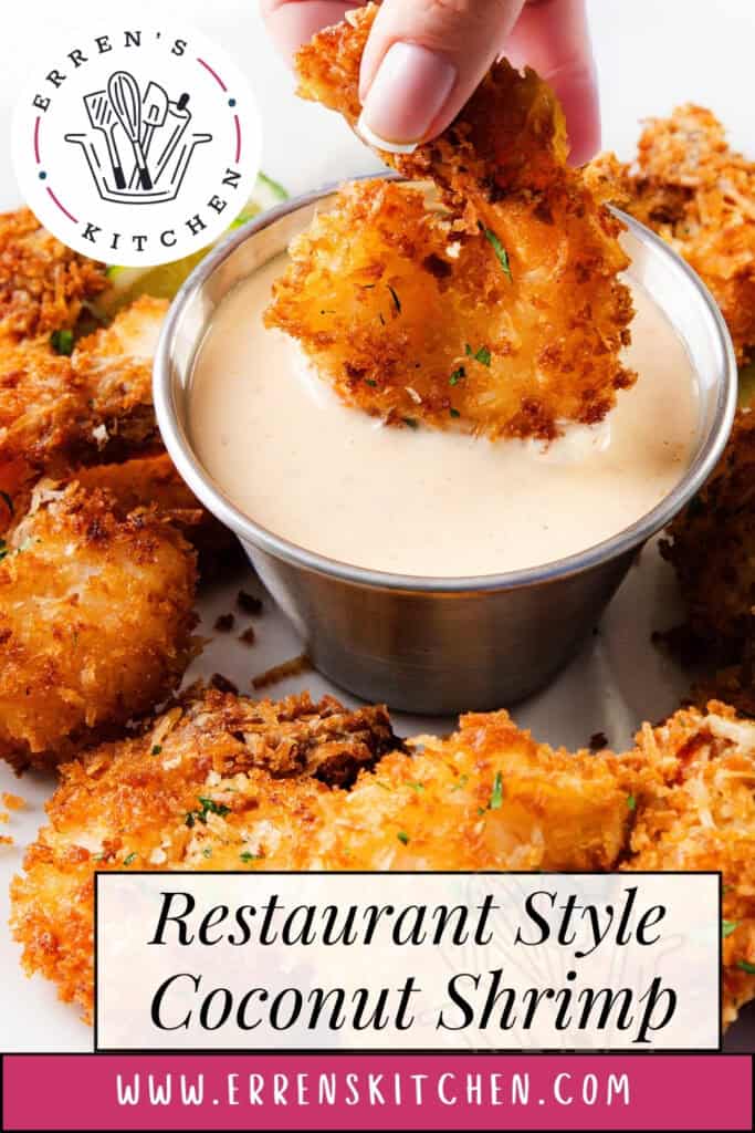 A hand dips a crispy, golden coconut shrimp into creamy sweet chili dipping sauce, surrounded by more on a white plate. Text overlay reads "Restaurant Style Coconut Shrimp" and "www.errenskitchen.com." Perfect shrimp recipe!.
