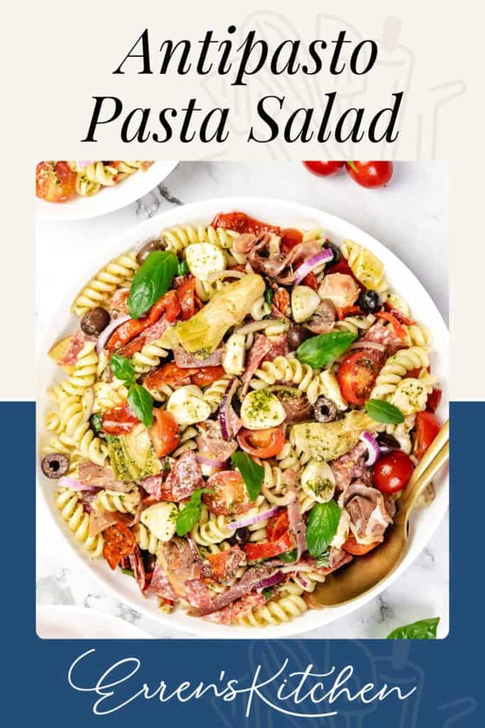 A bowl of Italian Antipasto Pasta Salad with rotini, salami, mozzarella balls, tomatoes, olives, artichokes, and basil, garnished with herbs. Text reads “Antipasto Pasta Salad,” “Easy Recipe,” and “Erren’s Kitchen.”.