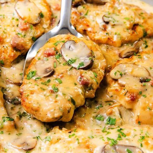 Creamy Chicken breasts in a rich mushroom sauce with herbs and bacon bits, garnished with chopped parsley, being spooned from a pan—perfect for lovers of Creamy Chicken Marsala.