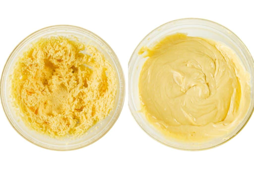 Two glass bowls viewed from above: the left holds a fluffy, yellow sock it to me cake batter, while the right contains a smoother, creamy yellow batter. Both sit on a white background.