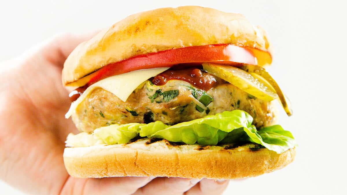 A hand holding a turkey burger