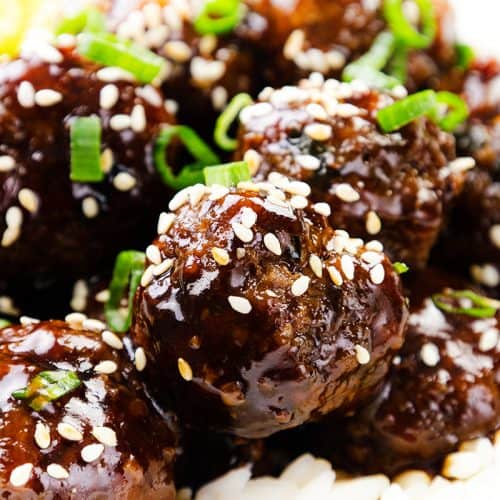 Close-up of Teriyaki Meatballs glazed with teriyaki sauce, topped with sesame seeds and chopped green onions, served on a bed of white rice. Perfect for anyone looking for a flavorful meatball recipe.