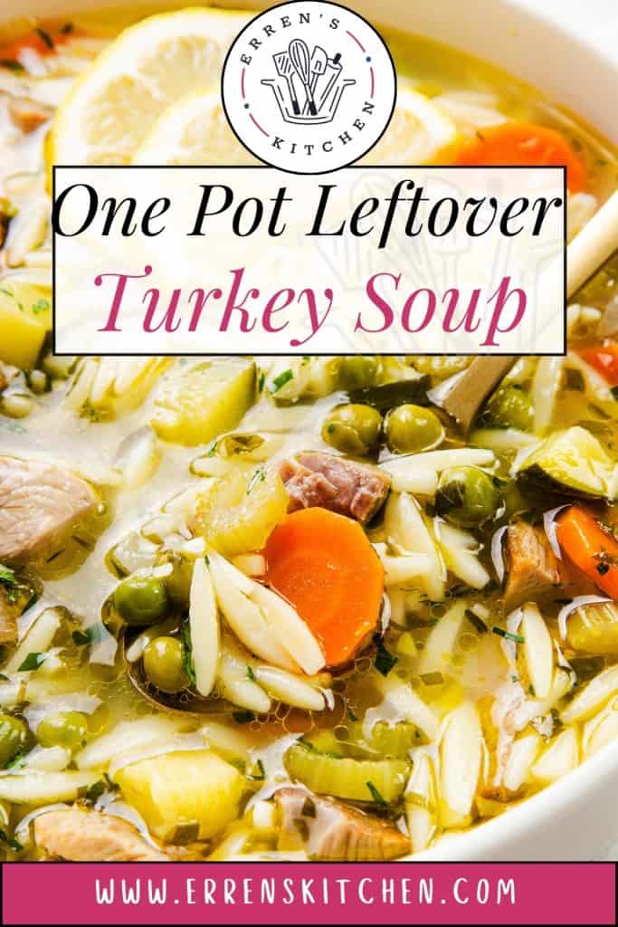 A bowl of comforting soup filled with carrots, peas, orzo, and leftover turkey, with a wooden spoon in the bowl. Text overlay reads, "One Pot Leftover Turkey Soup" and "www.errenskitchen.com.