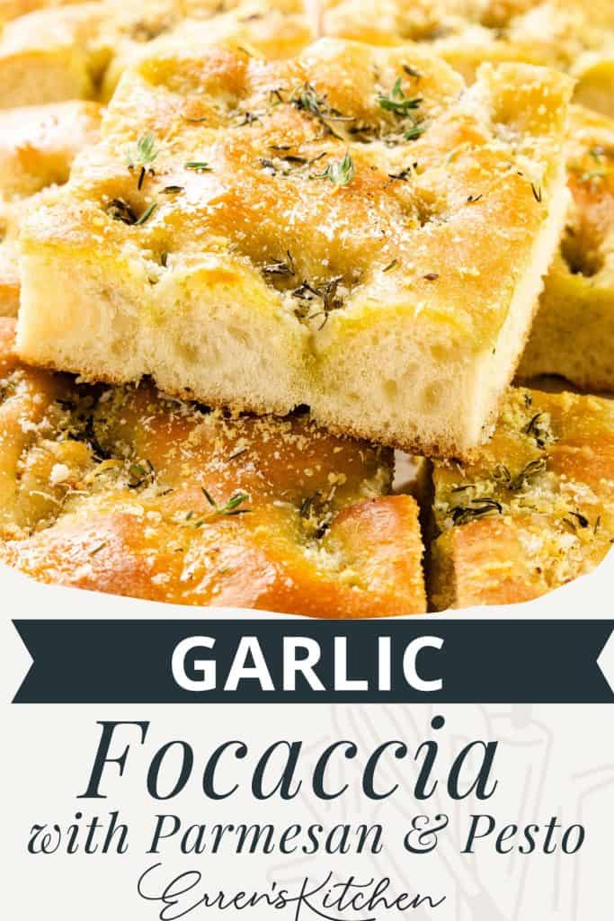 Close-up of golden, fluffy garlic focaccia topped with herbs, parmesan, and a swirl of pesto, cut into squares. Text overlay reads: "Garlic Focaccia with Parmesan & Pesto, Erren's Kitchen.