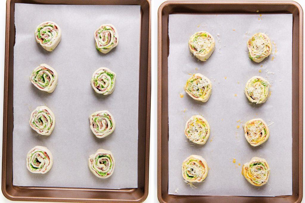 Dua loyang yang dilapisi kertas roti menampung sembilan Puff Pastry Pinwheels yang belum dimasak, masing-masing diisi dengan bahan hijau dan merah muda seperti krim keju pesto dan prosciutto, siap untuk dipanggang. Beberapa kincir ditaburi keju parut.