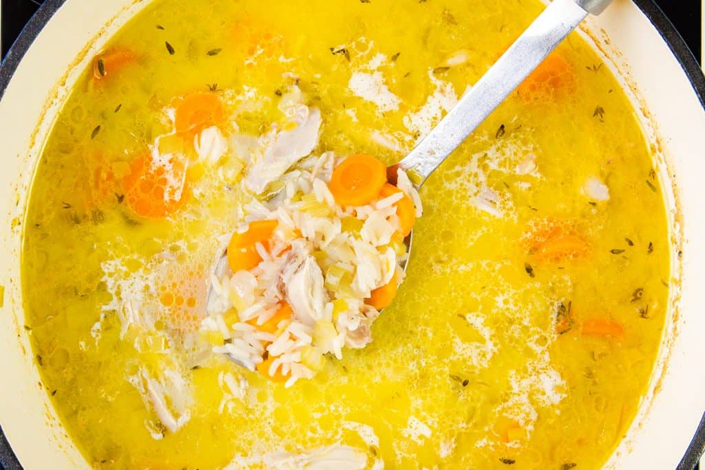 A spoon in a bowl of Chicken and Rice Soup.
