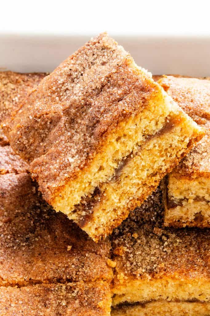 A close-up of cinnamon coffee cake slices with a cinnamon sugar topping, showing a soft, moist texture and a cinnamon swirl layer in the middle, reminiscent of the warm flavors found in Fig Filled Cookie Bars.