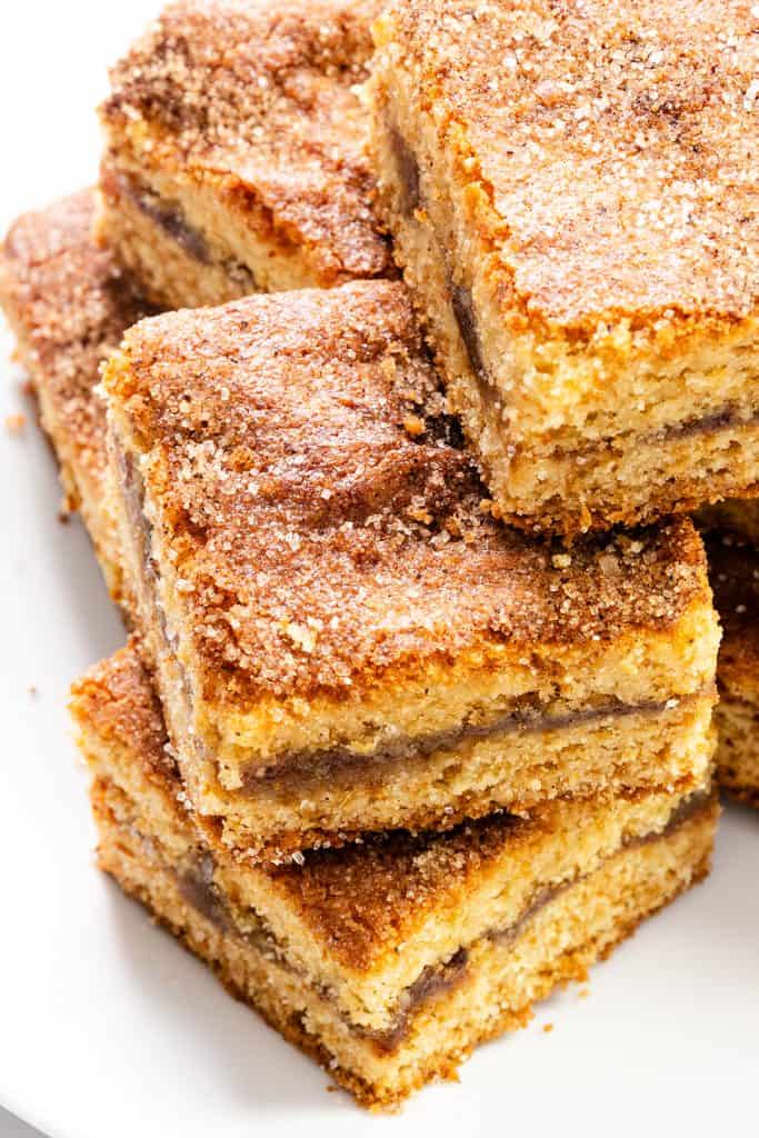 A stack of cinnamon sugar coffee cake squares with a visible cinnamon layer in the middle, arranged on a white plate—reminiscent of classic Fig Filled Cookie Bars with their inviting, nostalgic appeal.