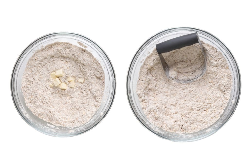 Two glass bowls with flour mixture for Irish Soda Bread; one has small butter cubes on top, the other shows a pastry cutter blending the ingredients. Both are viewed from above on a white background.
