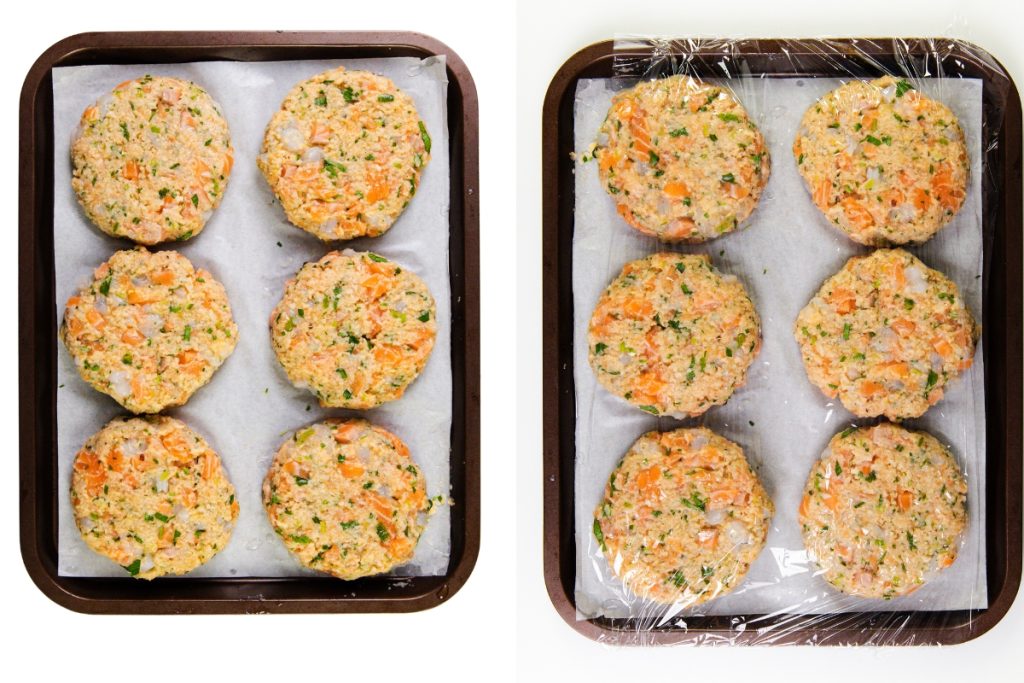 Two trays with six uncooked salmon cakes each on parchment paper. The left tray is uncovered, while the right tray is covered with plastic wrap. The patties contain visible herbs and diced vegetables. Perfect to pair with spicy mayo.