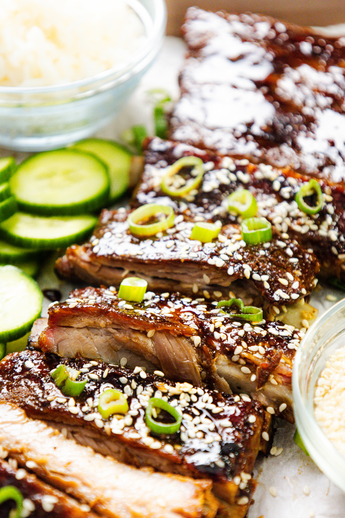 Asian style pork ribs served with rice and cucumber on a plate.