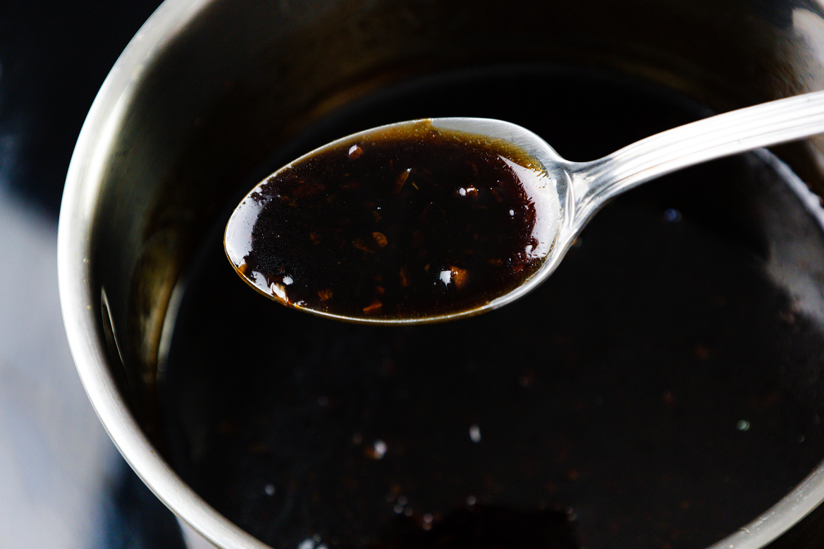 A sticky glaze for Asian style pork ribs simmering in a saucepan.