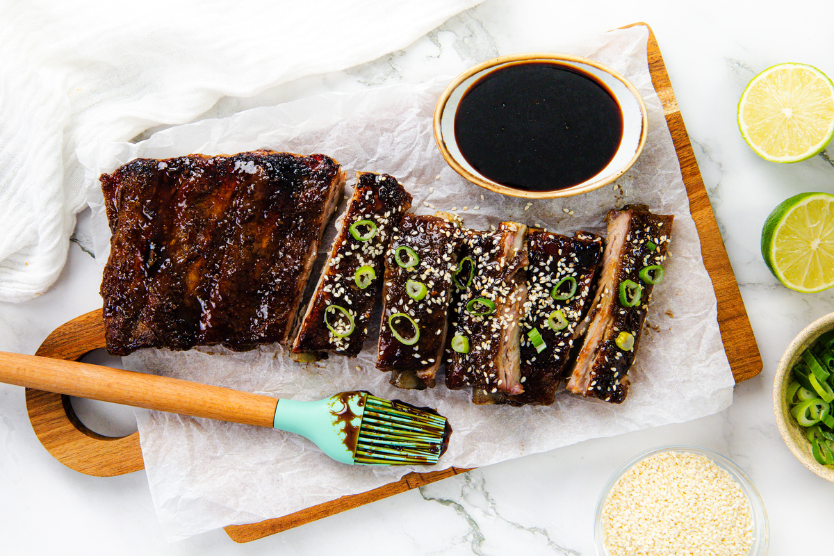 Cooked Asian style pork ribs ready to slice and serve with garnishes.