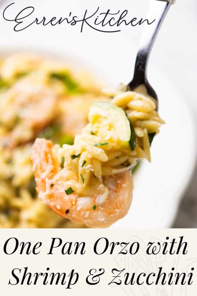 A fork holds orzo pasta, shrimp, and zucchini. In the background, a plate with more of this delicious one-pan orzo dish is blurred. Text reads: “Erren’s Kitchen. One Pan Orzo with Shrimp & Zucchini.”.