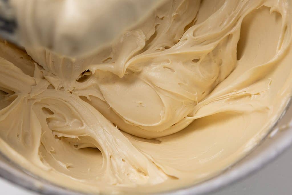 Creamy beige batter for pumpkin spice bars being mixed in a bowl.