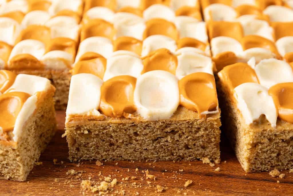A rectangular pumpkin spice bar topped with a checkerboard pattern of white and caramel-colored frosting.